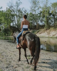 young woman on horseback near river