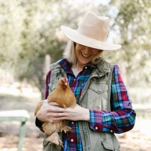 woman with a hat on holding a tan chicken