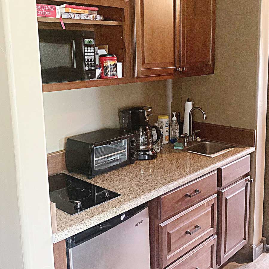 Avery's Escape Kitchenette with sink, coffee maker, toaster oven, two burner glass top stove, mini fridge, microwave and cabinets containing necessities
